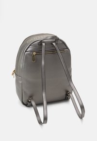 Grijze rugzak van gestructureerd leer, met gouden hardware, twee verstelbare schouderbanden en een ritsvak aan de achterkant.