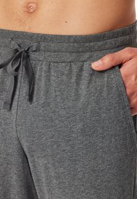 Pantalons de jogging gris en coton, dotés d'une taille élastique avec cordon de serrage et poches latérales. Texture douce, coupe décontractée et design taille mi-haute.