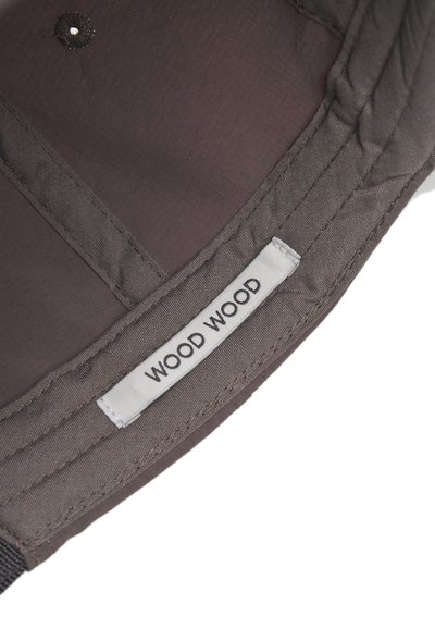 Artimas rudo audinio maišo kampas su siuviniu baltu ženklu "WOOD WOOD" ir matomomis siuvimo detalėmis.