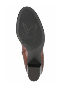 Zapato de cuero marrón con suela de goma que presenta un logo de mariposa. La suela tiene patrones texturizados para mayor agarre y un tacón rectangular.