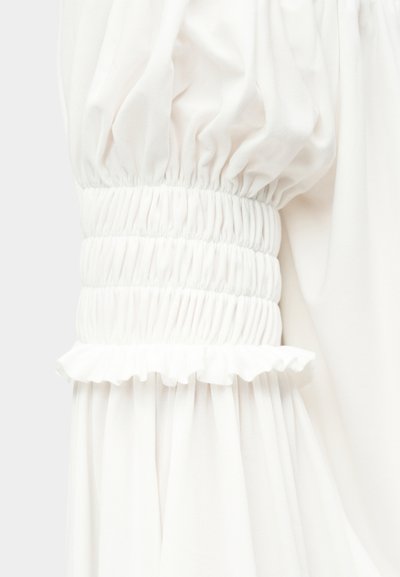 Λευκό μανίκι από ύφασμα με σούρα στο ελαστικό τελείωμα και διακοσμητικό βολάν.