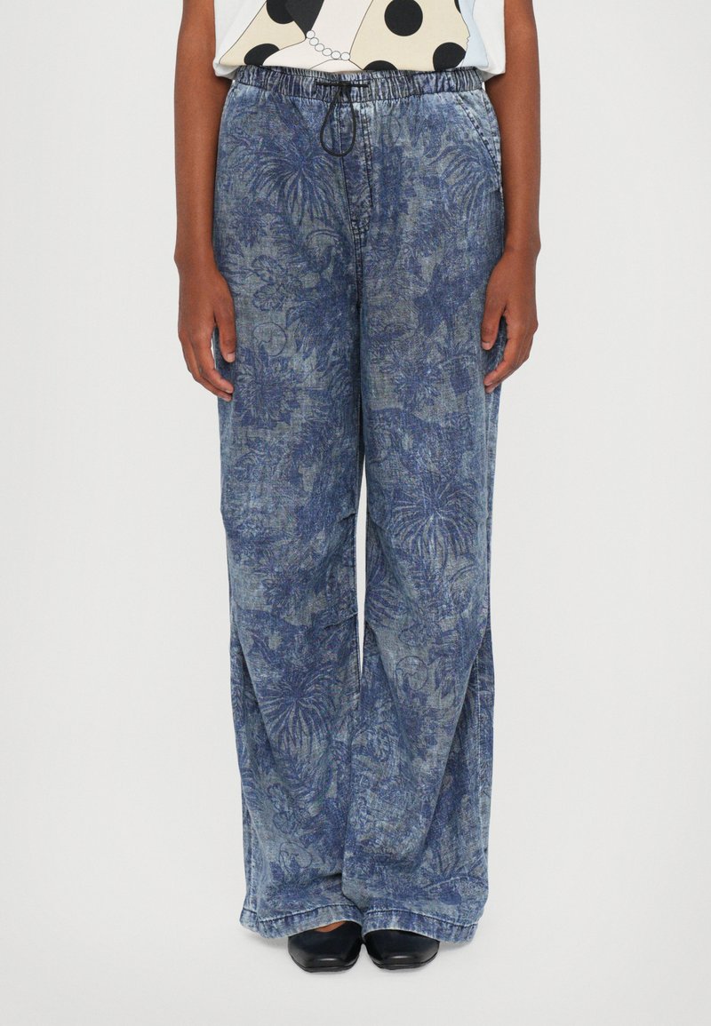 Blue patterned wide-leg pants made of denim, featuring an elastic waistband with a drawstring. The fabric has a textured leaf design.