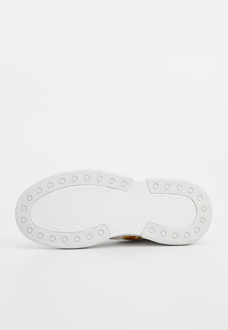 Weiße Sneaker-Sohle mit einem strukturierten Muster, das rundliche Grip-Punkte und eine glatte Umrandung aufweist. Das Design betont die Traktion und Haltbarkeit.