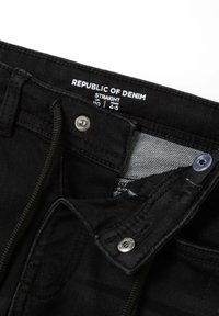 Jeans de mezclilla negra con corte recto, que cuentan con un botón plateado, cremallera y etiqueta "REPÚBLICA DE MEZCLILLA". Incluye un forro de tela en el interior.