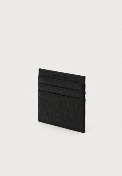 Cartão de couro preto texturizado com várias ranhuras horizontais para cartões em fundo claro.