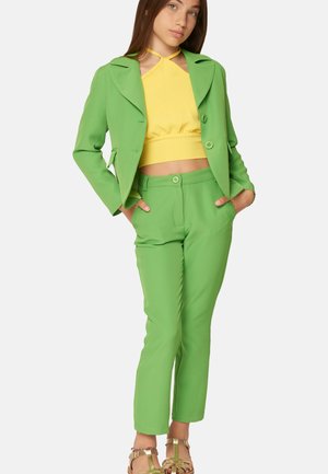 Blazer verde su misura e pantaloni abbinati con un top giallo corto. Tessuto liscio, design aderente e chiusura a bottone sui pantaloni.
