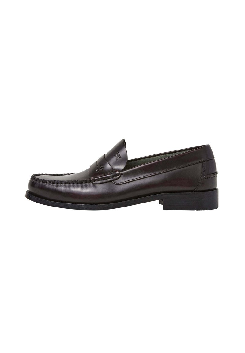 Donkergroene leren loafers met stiksel en een kwastaccent, beschikt over een platte rubberen zool en een gladde afwerking.