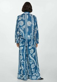 Ensemble chemise à motifs bleus et pantalon à jambes larges, décoré de motifs floraux blancs, coupe décontractée, tissu lisse avec col et manches longues.