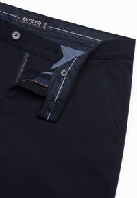 Navy broek met een rits en knoopsluiting, met een strakke textuur, standaard zakken en subtiele stikdetails aan de binnenkant van de tailleband.