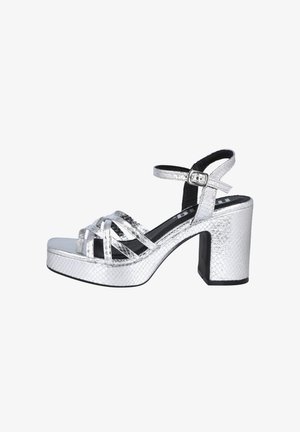 Sandalias de plataforma plateadas con un patrón de piel de serpiente texturizada, correa en el tobillo y un tacón de bloque. El diseño cuenta con múltiples correas entrecruzadas.