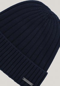 Granatowy dziany beret z prążkowaną teksturą, z wywiniętą mankietą i małą metalową etykietą z napisem "PROCHNIK."