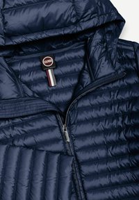 Marineblå quiltet jakke med hætte, lynlås foran og Colmar Originals mærke indeni kraven.