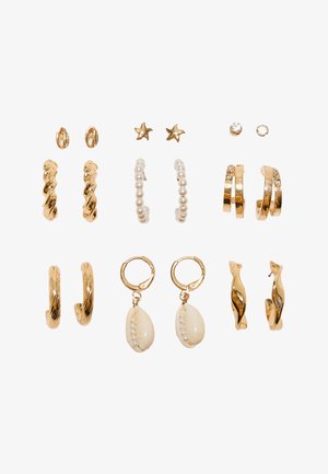 Neuf paires de boucles d'oreilles en ton or et perles comprenant des créoles torsadées, des clous en forme d'étoile, des créoles à perles, des accents en cristal et des boucles d'oreilles pendantes en coquillage sur fond blanc.