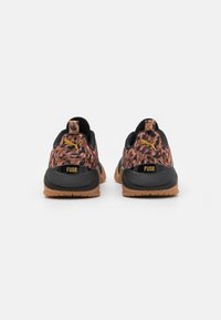 Paar Puma Fuse Sneaker mit Obermaterial im Leopardenmuster, schwarzer Fersenstütze und Gummisohlen in Karamellfarbe, von hinten auf weißem Hintergrund gezeigt.