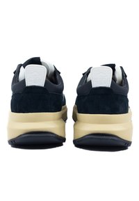 Schwarze Wildleder- und Textil-Sneaker mit einer beigen Sohle. Sie besitzen eine abgerundete Form und eine weiße Fersenschlaufe mit Logodetail.