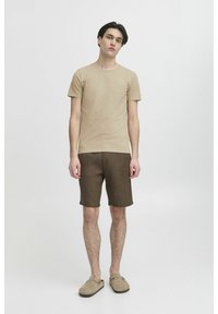 Beige illeszkedő póló, barna rövidnadrág és szürke slip-on cipők. Sima pamut textúra, természetes színek és egyszerű dizájn. Egyszerű szabás és illeszkedés.