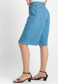 Lichtblauwe denim bermuda shorts met een rechte snit, middenhoogte taille en twee achterzakken. Gecombineerd met zwart leren sandalen met bandjes.