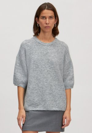 Lichtgrijze, oversized trui met korte, puffy mouwen. Zacht, textuurstof en geribbelde halslijn. Gepaard met een donkergrijze rok.