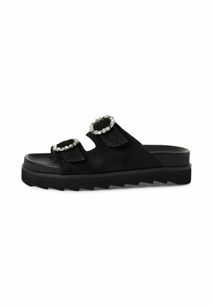 Black slide sandal with two wide straps featuring large silver-studded buckles and a thick jagged sole.