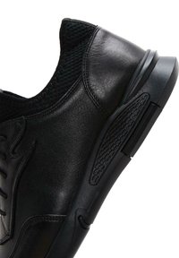 Zapatilla deportiva negra hecha de material de cuero y malla, con un upper texturizado, cordones y suela de goma con acentos de ventilación.