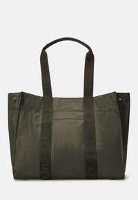 Oliivinvihreä kangaskassi, jossa on kaksi tukevat kangaskahvat, sileä mattapintainen rakenne ja hienovarainen logotunnus olkahihnoissa.