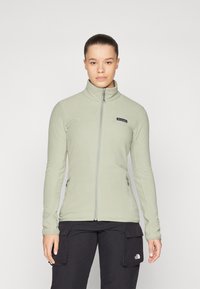 Vaaleanvihreä fleece-takki, jossa on korkea kaulus, täysi vetoketju ja sivutaskut. Takissa on pieni brändilogo vasemmassa ylärinnassa.