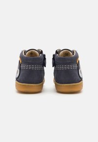 Bottes pour tout-petits en suede bleu marine avec une semelle en caoutchouc, dotées de coutures blanches, de détails latéraux et d'accents bleus. Comprend une boucle à l'arrière pour un enfilage facile.