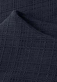 Tela azul marino oscuro con una esquina doblada, mostrando un patrón texturizado de punto en forma de cuadrícula.