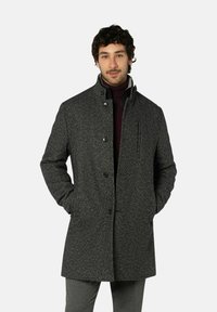 Grauer strukturierter Mantel mit hohem Kragen, Knopfverschluss und seitlichen Taschen, getragen über einem dunklen Rollkragenpullover.