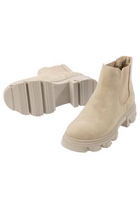 Bottines en suede beige avec des panneaux latéraux élastiques, une semelle en caoutchouc texturée et un design épais et robuste.