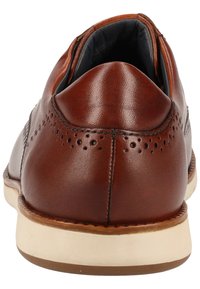 Chaussure habillée en cuir marron avec des détails perforés, talon arrondi et semelle couleur crème. L'intérieur présente une doublure en tissu sombre.