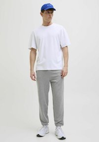 Hvid bomulds T-shirt med korte ærmer, parret med grå sweatpants. En blå kasket og hvide sneakers fuldender looket.