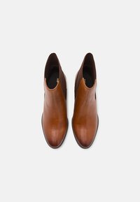 Brune lær ankelsko med et slankt design, rund tå, elastiske sidestykker og glat tekstur. Ingen synlige metaldele eller mønstre.