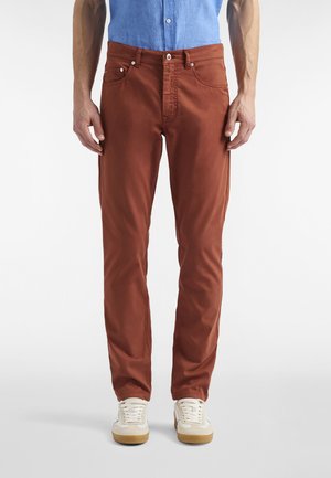 Pantaloni color ruggine a taglio slim, realizzati in cotone, con un classico design a cinque tasche, dettagli di cuciture sottili e chiusura con bottone.