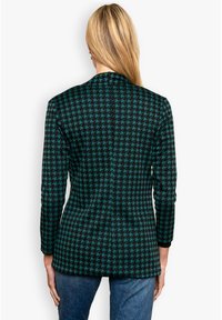 Mustreeritud must ja türkiissinine houndstooth bleiser, millel on kohandatud lõige, pikad varrukad ja lõigatud krae, valmistatud tekstuursest kangast.