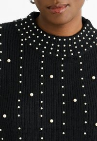 Black knitted sweater with a textured rib pattern, adorned with evenly spaced white faux pearls, featuring a round neckline.