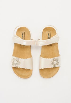 Sandales blanches à bout ouvert avec brides à la cheville, semelles intérieures marron rembourrées et ornements décoratifs de fleurs pailletées sur les brides avant.