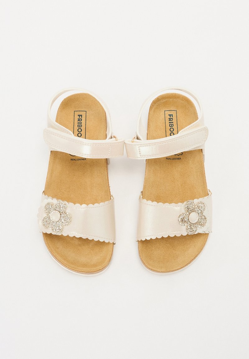 Sandales blanches à bout ouvert avec brides à la cheville, semelles intérieures marron rembourrées et ornements décoratifs de fleurs pailletées sur les brides avant.