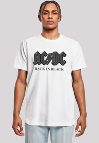 White cotton t-shirt featuring large black "AC/DC" logo with lightning bolt and "BACK IN BLACK" text below. Short sleeves, crew neck design.