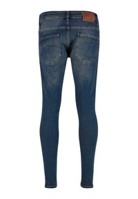 Jean en denim coupe slim de couleur bleu foncé. Dispose de poches arrière et d'une pièce en cuir marron texturée sur la ceinture. Texture de tissu lisse.