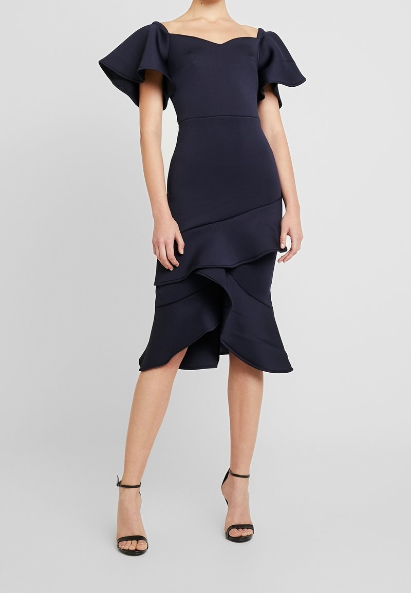 Mörkblå off-shoulder klänning med volangiga korta ärmar och lager-på-lager nederdel. Tillverkad av strukturerad tyg, med en åtsittande byst.