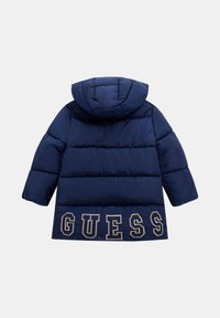 Cappotto imbottito blu navy con cappuccio, caratterizzato da pannelli orizzontali cuciti e logo 'GUESS' in beige sull'orlo. Tessuto di texture liscia e lucida.