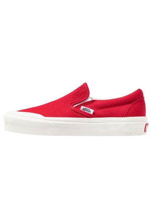 Rød lærreds slip-on sneaker med hvid gummisål, der har elastiske sider og en lille logotag på overdelen.