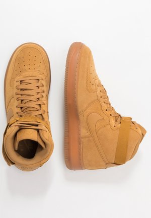 Baskets montantes en daim beige avec perforations, devant lacé, logos Nike swoosh et semelles en caoutchouc, vues de dessus et de côté.