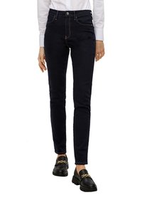 Donkerdenim hoge taille jeans met een slim fit, voorzien van vijf zakken, contrasterende stiksels en een metalen knoopsluiting. Draagt met zwarte instappers.