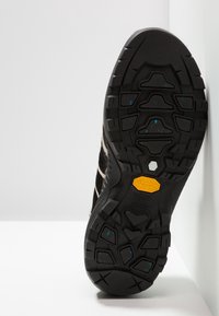 Suela exterior de goma negra con un patrón texturizado, que presenta el logo de Vibram, destacado en amarillo. Diseñada para tracción y durabilidad.