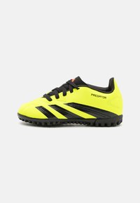 Zapatos de fútbol amarillos con acentos negros, parte superior sintética texturizada, diseño con cordones y suela de goma, que presenta el logo "Predator".