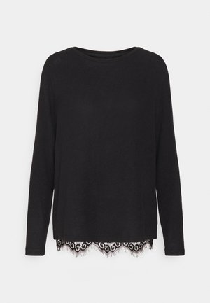 Chemise noire à manches longues en tissu doux, avec un ourlet décoré d'une dentelle au motif tourbillonnant. Encolure ronde et coupe décontractée.