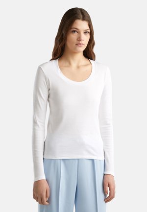 Weißes Langarm-T-Shirt mit Rundhalsausschnitt, weichem Material und minimalistischem Design, kombiniert mit hellblauen Hosen.