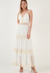 Maxikleid in Weiß mit einem geschichteten Design, verziert mit Spitzenbesätzen, einem V-Ausschnitt, verstellbaren Trägern und einem strukturierten Muster.